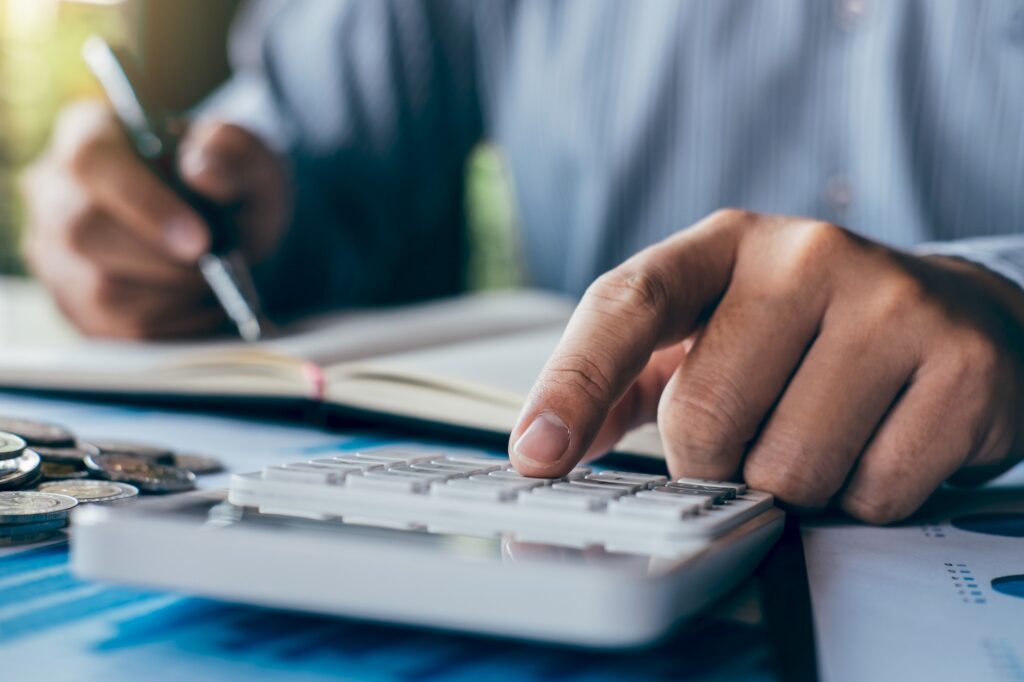 Businessman accountant making notes at report doing finances and calculate about cost of investment