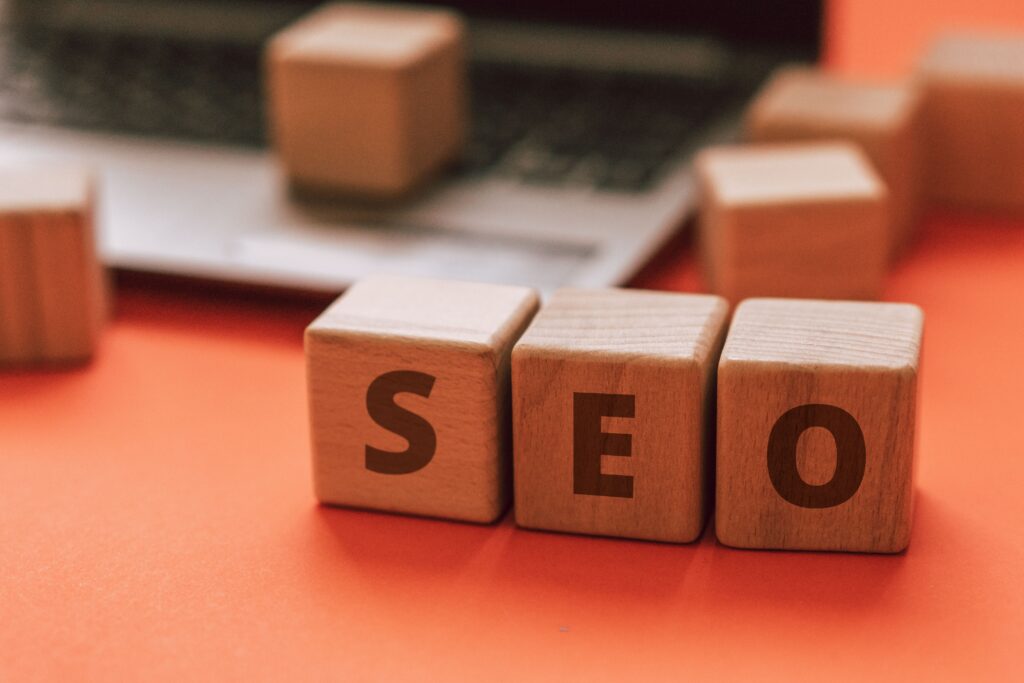 Wooden blocks spelling "SEO" in front of a blurred background with a laptop, representing SEO services in Charlotte.