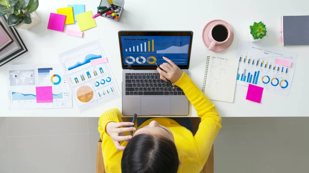 Overhead view of a professional analyzing local SEO services data on a laptop surrounded by charts and graphs.