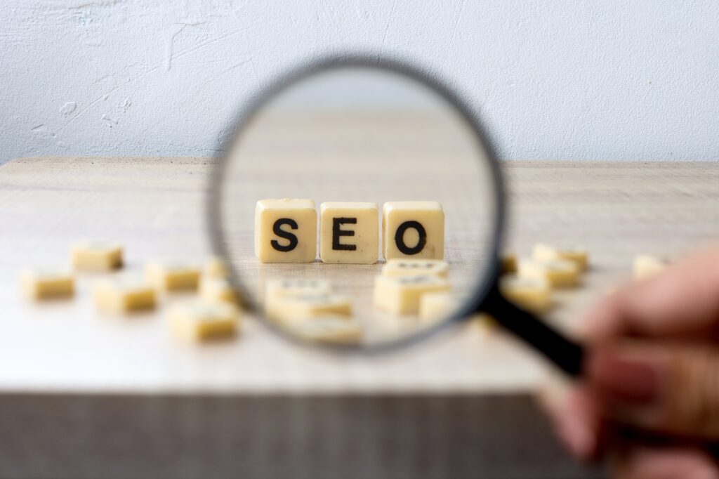 Magnifying glass focusing on blocks spelling "SEO" on a wooden surface, representing SEO services in Dallas.