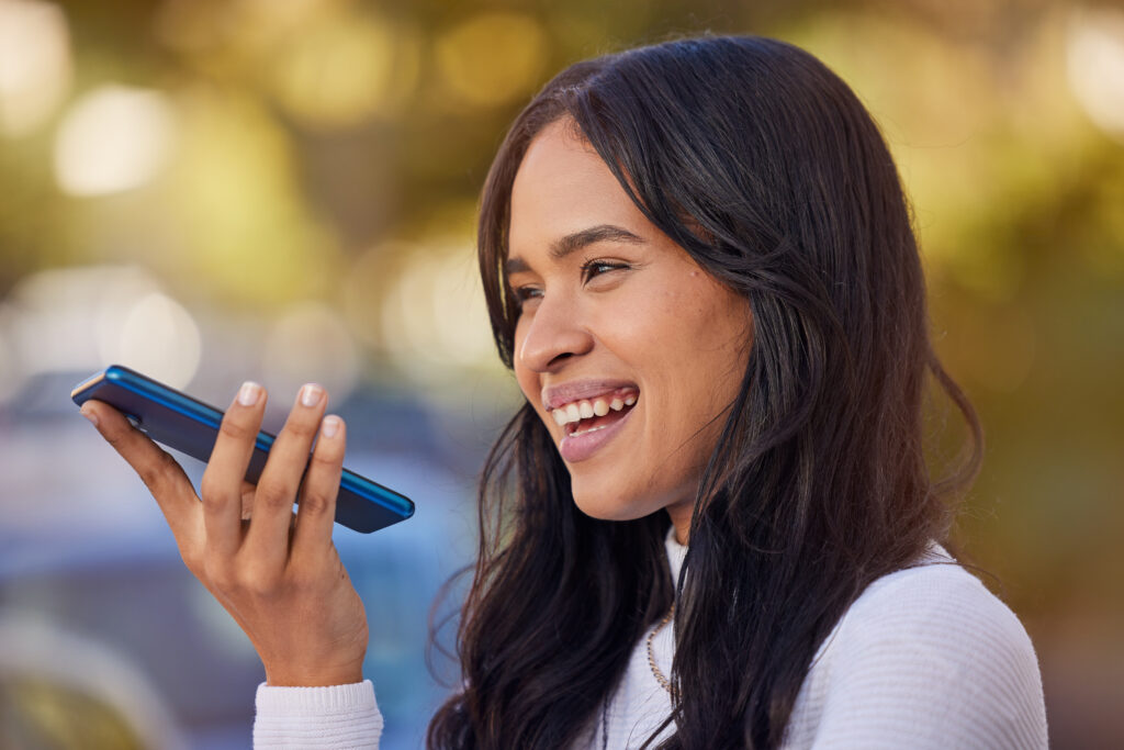 A woman using voice commands on her smartphone, illustrating the future of voice search optimization in SEO.