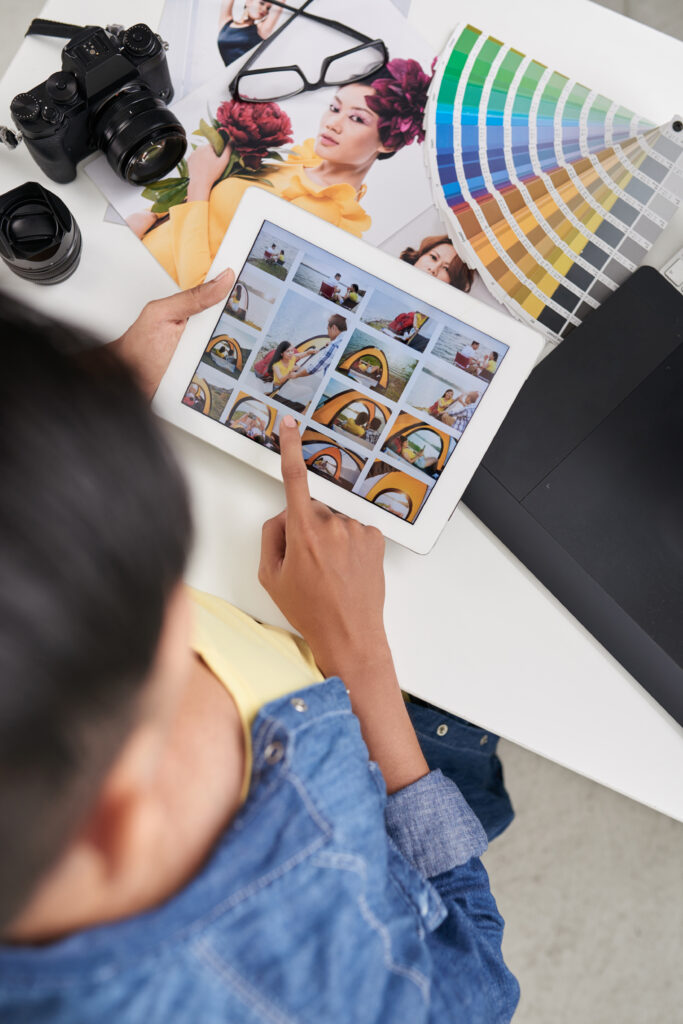 Person using a tablet to browse website designs with a color palette and camera on the table, highlighting website development in Denver.
