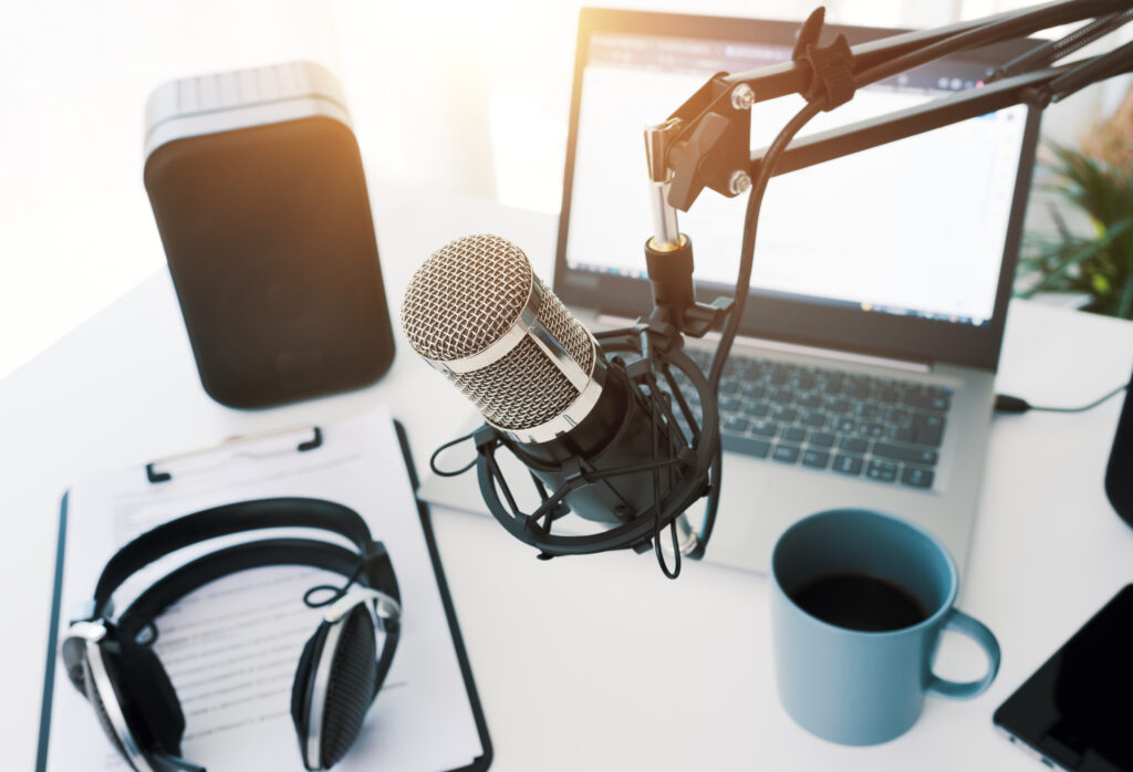 Start a podcast with a professional podcast recording setup with a microphone, headphones, and a laptop.