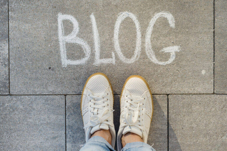 Top-down view of sneakers standing near the word Blog written in chalk.