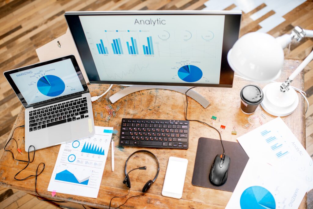 This image shows a business professional in a modern office setting, analyzing Google Ads performance on a desktop monitor. The visual represents strategies for maximizing ROI with Google Ads management by closely monitoring campaign performance metrics and data analytics.