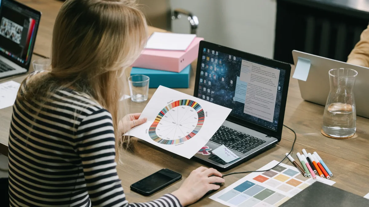 Marketer working with a color wheel and creative swatches beside her laptop.